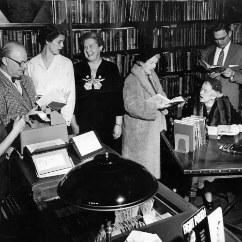 old black and white image of people gathered in the library.